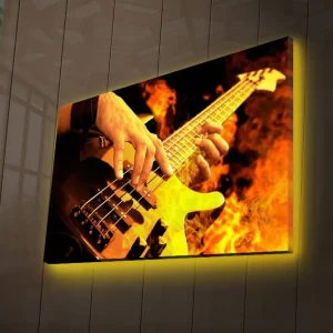 Canvastavla med LED-belysning 45x70 cm - Gitarrist som spelar en elbas omgiven av eldiga flammor Orange / Svart / Gult - Inredning Köp nu